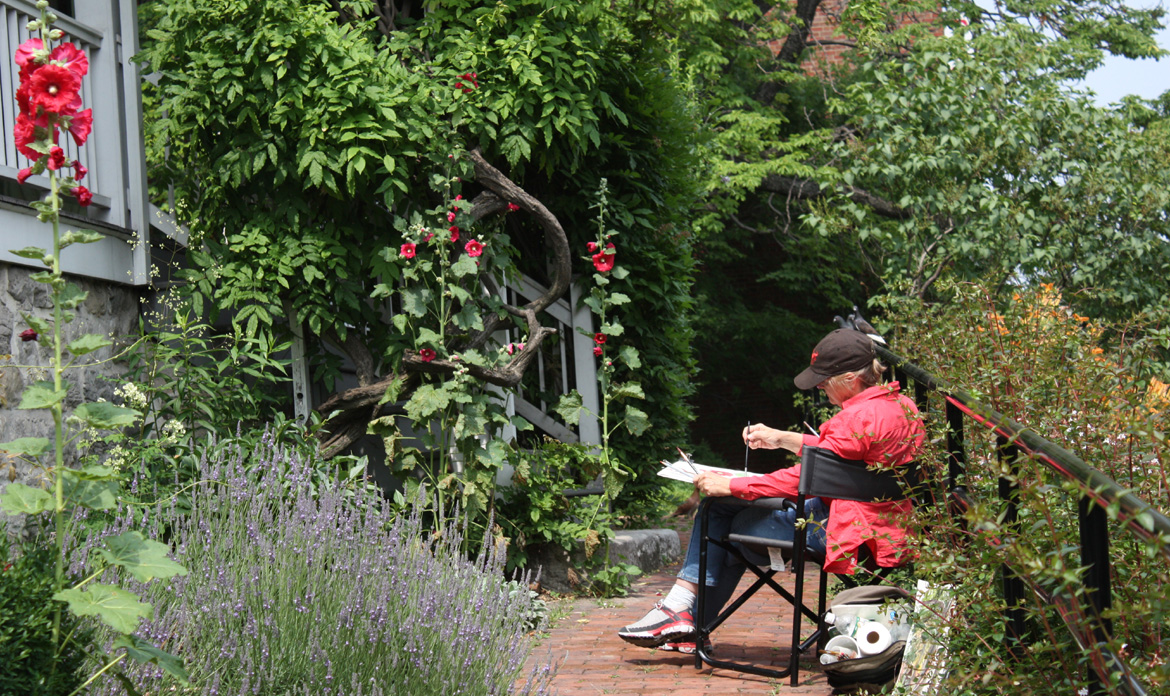 View of artist painting on the grounds of the Dyckman Farmhouse Museum